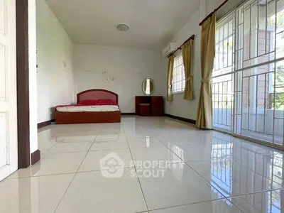 Spacious bedroom with large windows and balcony access, featuring tiled floors and minimalist decor.