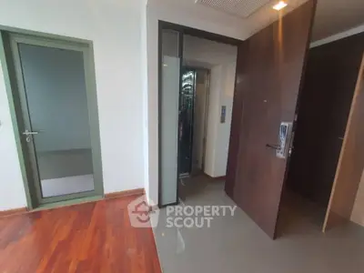 Spacious corner unit with polished wooden flooring and modern sliding doors leading to a well-lit hallway, perfect for urban living.