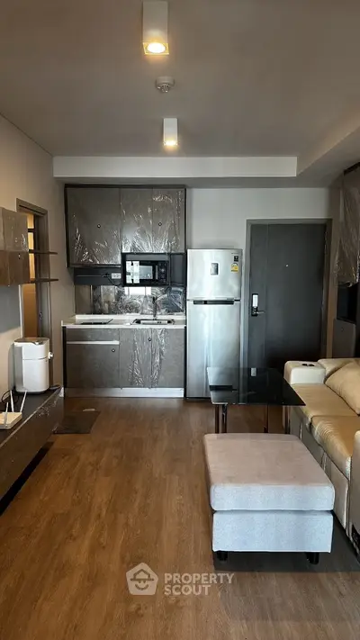 Modern open-layout kitchen and living room with sleek appliances and cozy seating area.