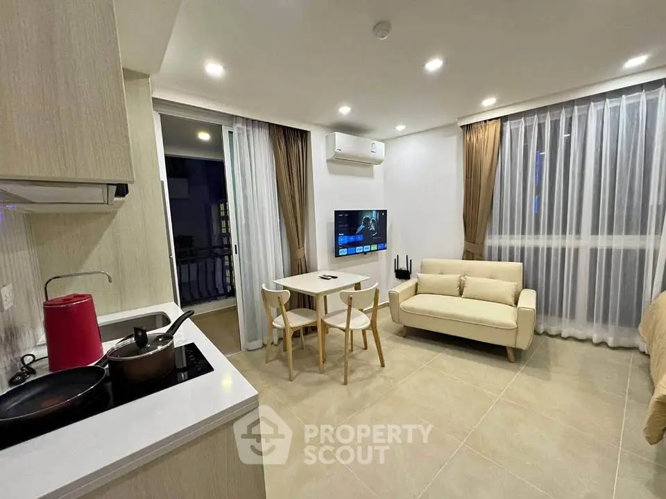 Modern open-plan living room with kitchen and dining area, featuring sleek furniture and bright lighting.