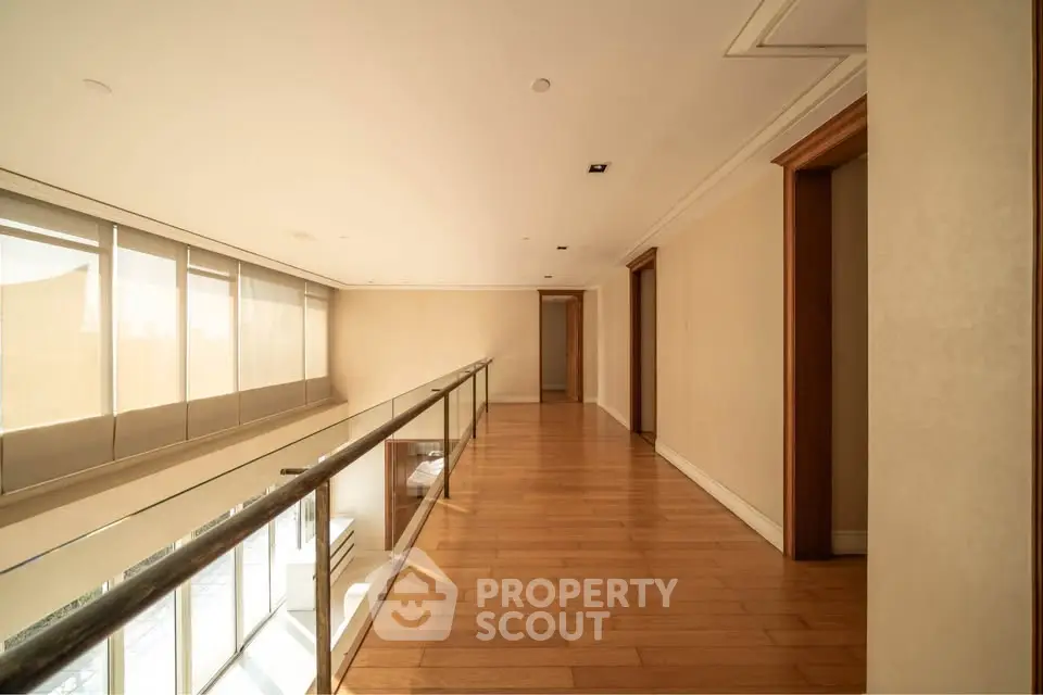 Spacious corridor with wooden flooring and glass railing in modern building