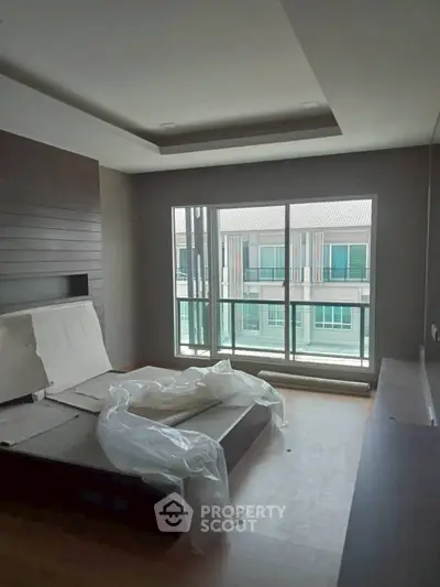 Modern bedroom with large window and partial view of neighboring building.
