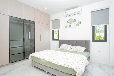 Modern bedroom with stylish decor and large wardrobe in a bright, airy space.
