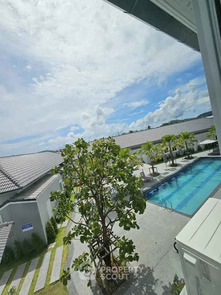 Luxurious residential pool area with modern architecture and lush greenery under a bright blue sky.