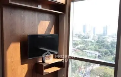 Modern living room with large window offering city view and wall-mounted TV.