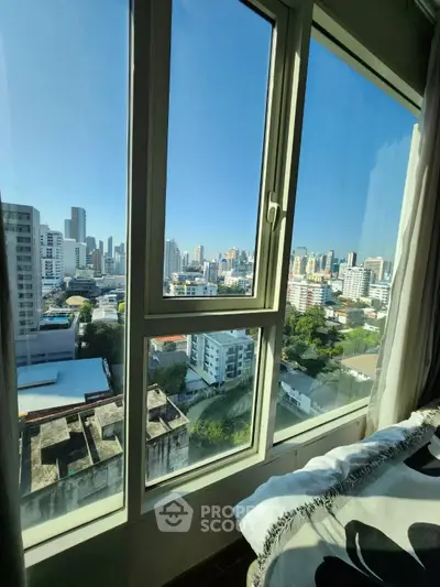 Stunning cityscape view from a high-rise apartment window, showcasing urban skyline and clear blue sky.