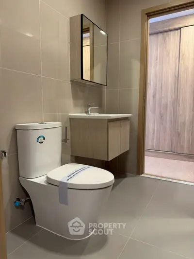 Modern bathroom with sleek fixtures and neutral tones, featuring a stylish vanity and contemporary toilet.