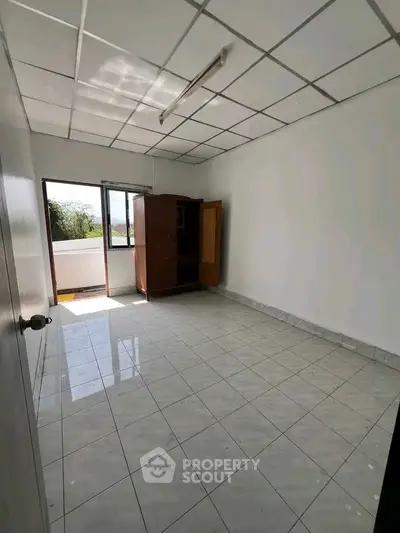 Spacious empty room with tiled floor and balcony access, ideal for customization.