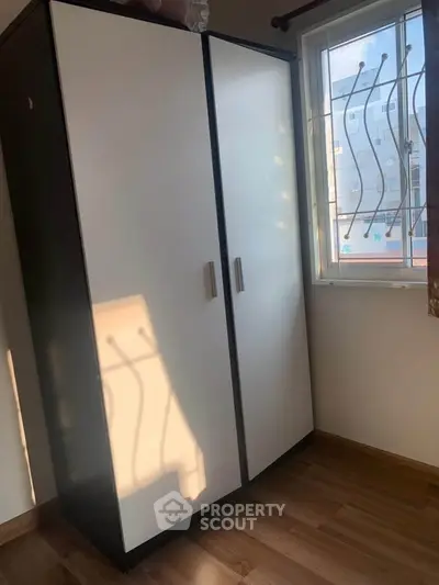 Cozy bedroom with wardrobe and natural light from window