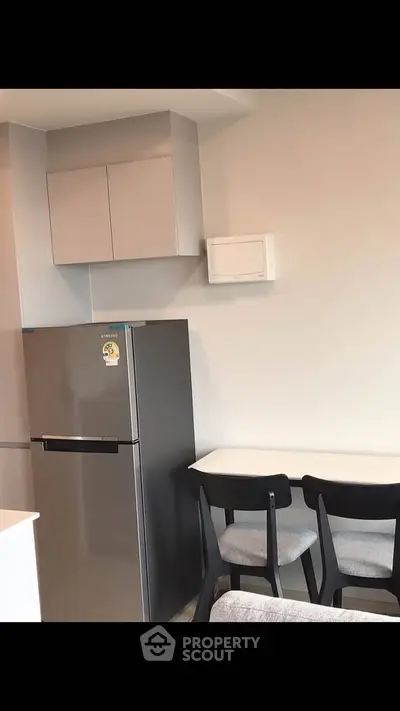 Modern kitchen with sleek fridge and dining area in stylish apartment.
