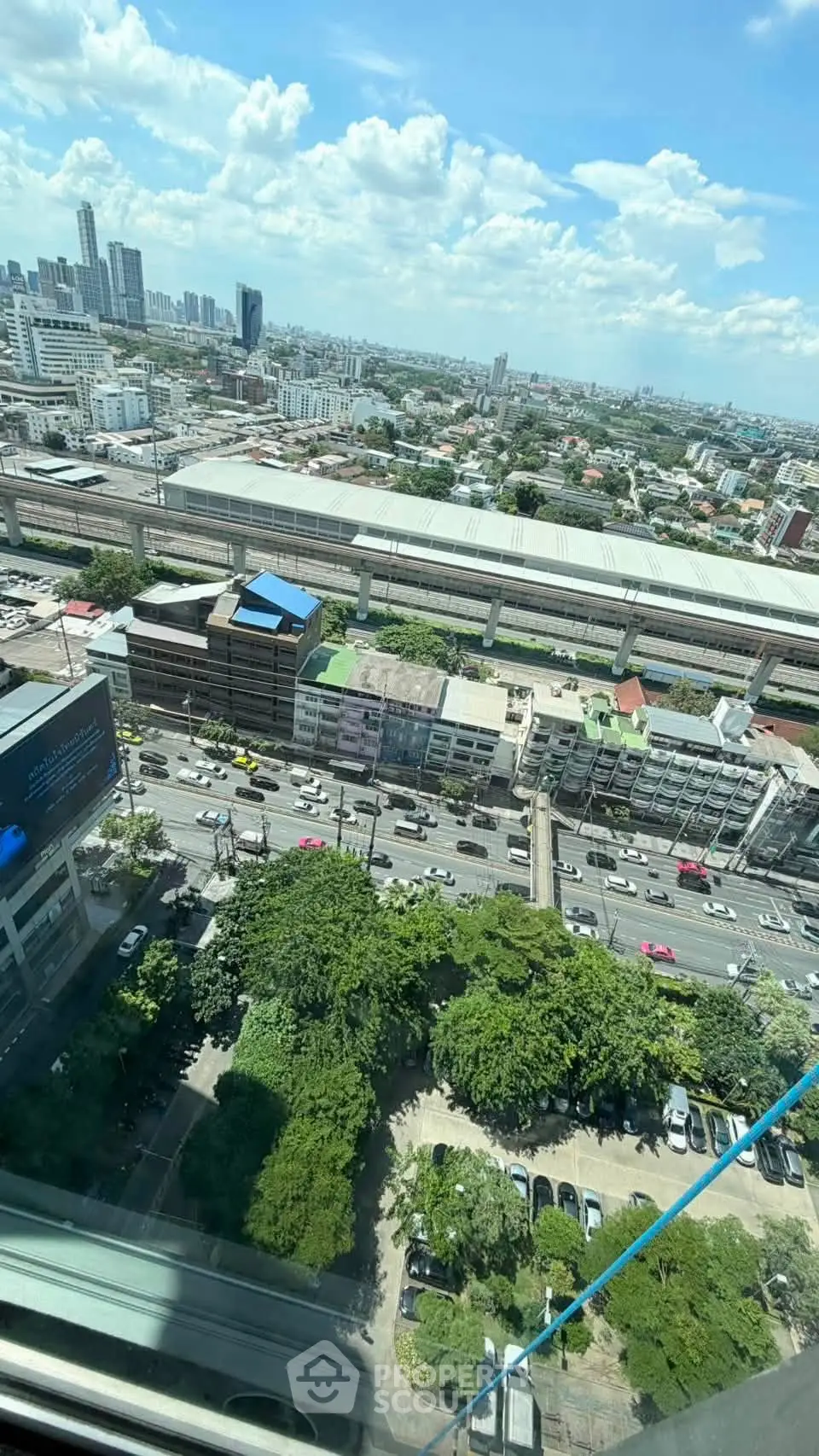 Stunning cityscape view from high-rise building with lush greenery and bustling streets below.