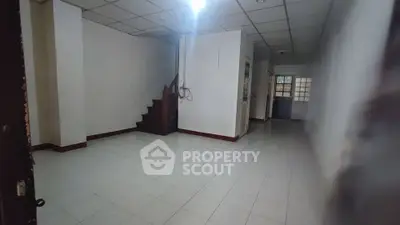 Spacious interior with tiled flooring and staircase, ideal for customization.