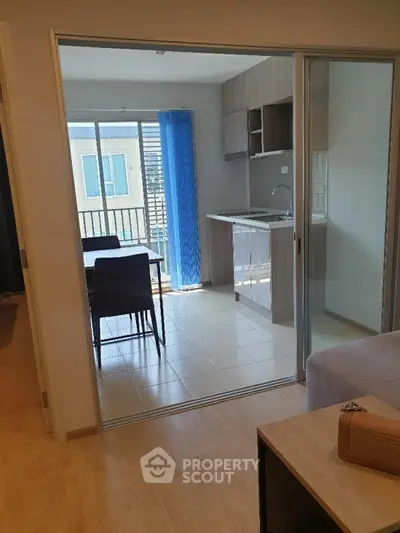 Modern apartment with open kitchen and dining area, featuring sliding glass doors and balcony view.