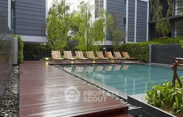 Luxurious modern apartment complex with serene outdoor pool and lush greenery.