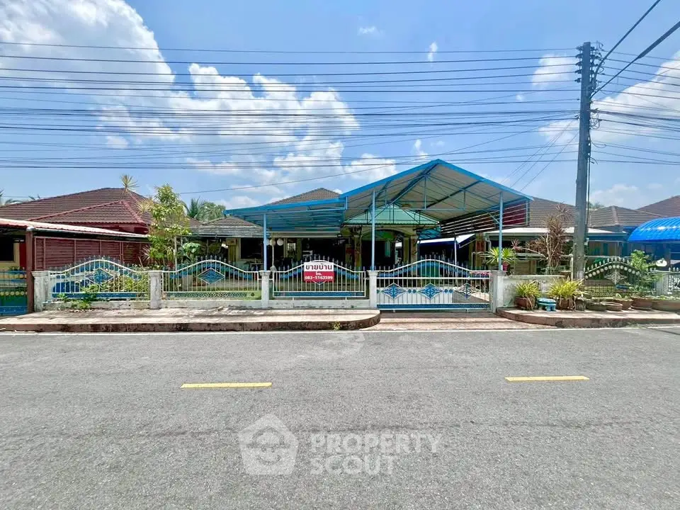 Charming suburban house with a spacious carport and fenced front yard under a clear blue sky.