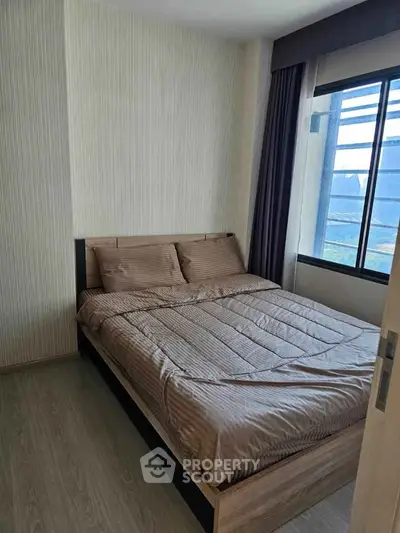 Cozy bedroom with modern decor and large window offering natural light.