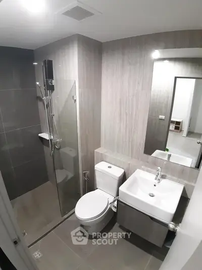 Modern bathroom with sleek design, featuring a glass shower enclosure and contemporary fixtures.