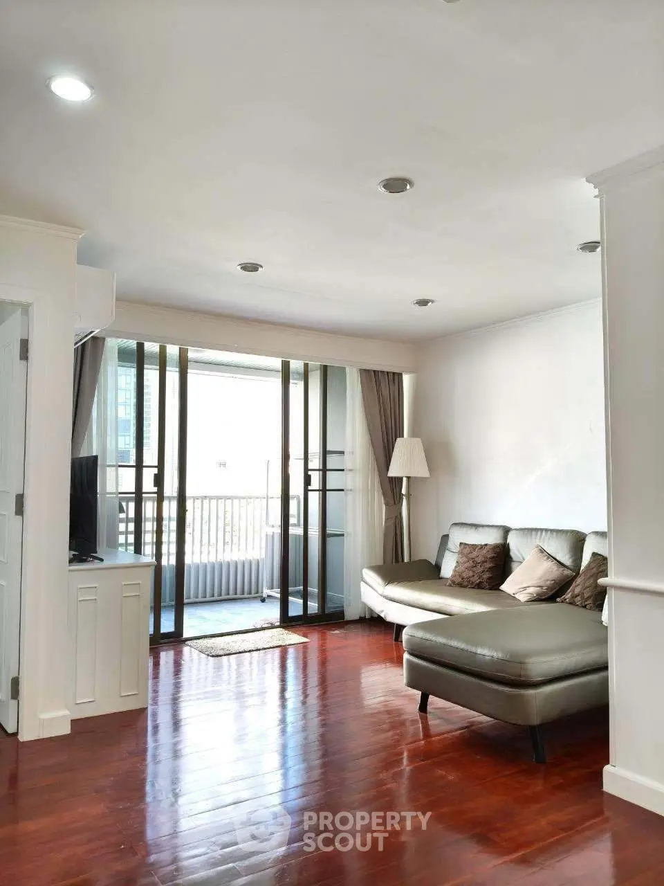 Spacious living room with elegant hardwood floors and large balcony access.