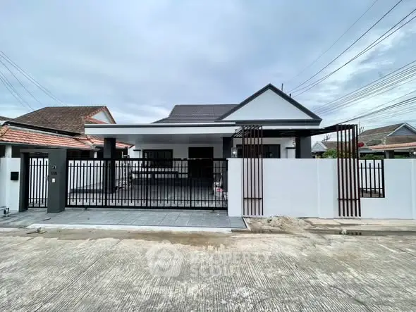 Modern single-story house with gated entrance and spacious driveway.