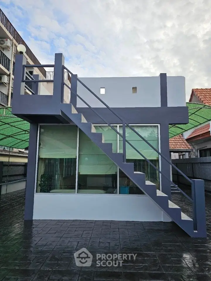Modern rooftop terrace with sleek staircase and glass windows, perfect for urban living.