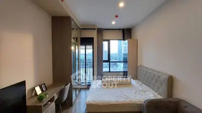 Modern bedroom with city view, featuring a cozy bed, stylish desk, and large window for natural light.