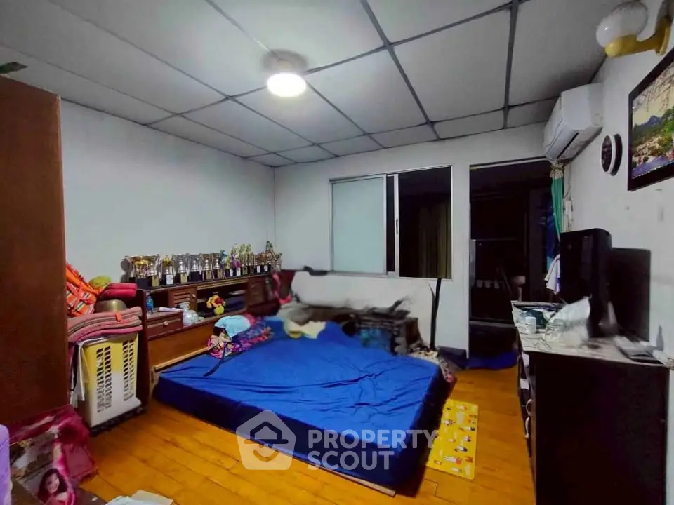Cozy bedroom with wooden flooring and air conditioning, featuring a comfortable bed and ample storage space.