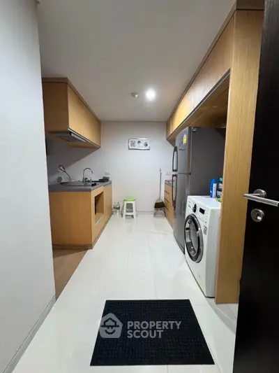 Modern kitchen with wooden cabinets and appliances, featuring a washing machine and refrigerator.
