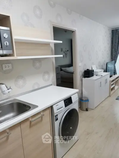 Modern kitchen with washing machine and sleek cabinetry in stylish apartment.