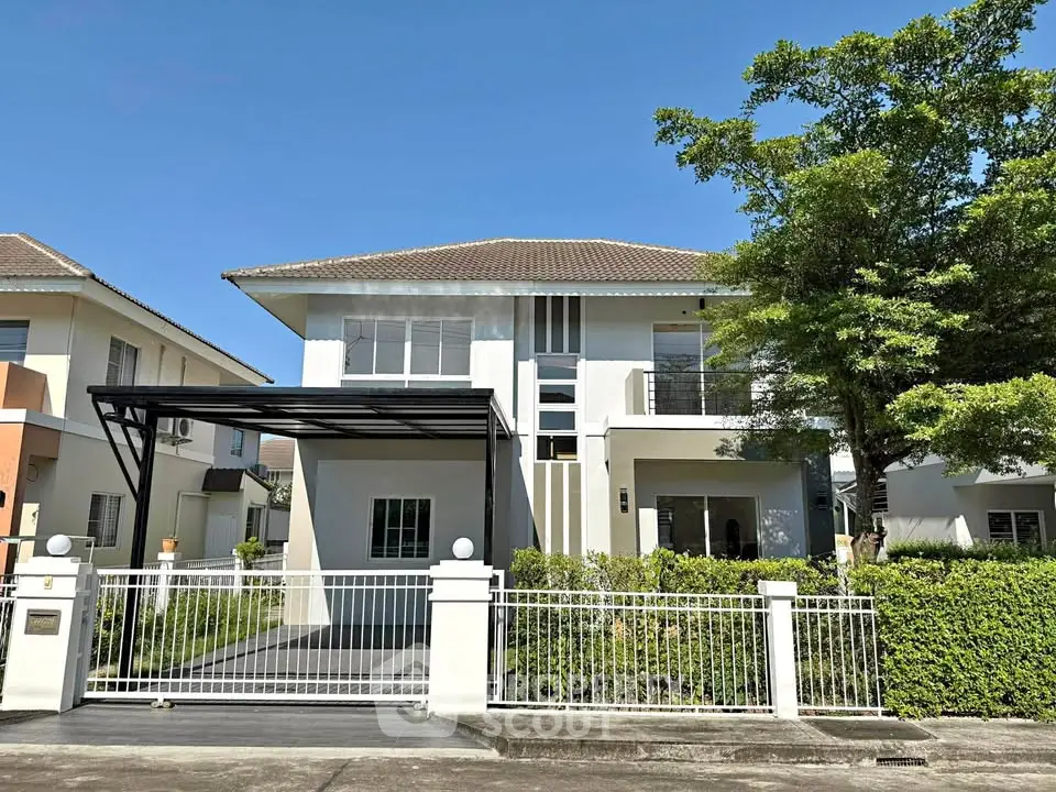 Modern two-story house with gated driveway and lush greenery