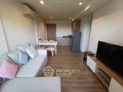Modern living room with open kitchen, stylish decor, and wooden flooring in a cozy apartment.