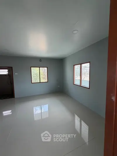 Spacious empty room with large windows and glossy tiled floor, perfect for customization.
