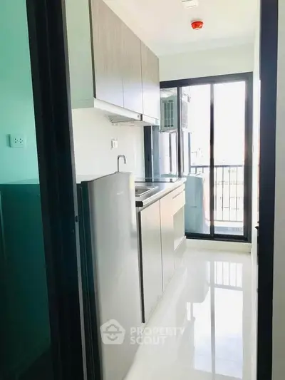 Modern kitchen with sleek cabinetry and balcony view in a bright apartment.