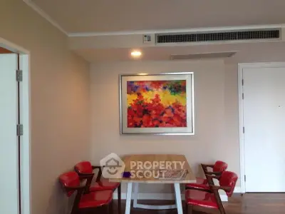 Chic dining area with vibrant artwork and red chairs in modern apartment.