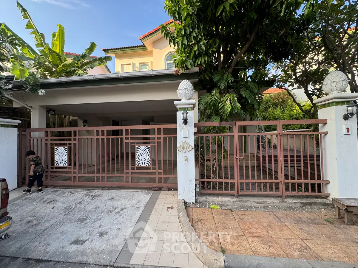 Charming suburban house with gated driveway and lush greenery, perfect for family living.