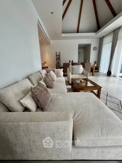 Luxurious living room with elegant decor and high ceilings, featuring a spacious beige sectional sofa and stylish accents.