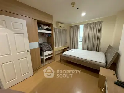 Cozy bedroom with wooden flooring, built-in wardrobe, and large window with city view.