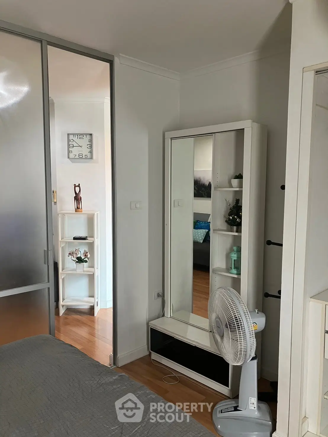 Cozy bedroom with modern decor and sliding door, featuring a stylish mirror and wooden flooring.