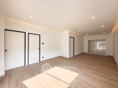 Spacious modern living room with wooden flooring and ample natural light