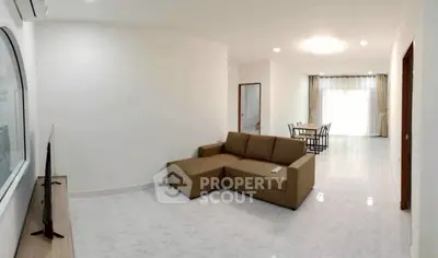 Spacious living room with modern sofa and dining area in open layout apartment.
