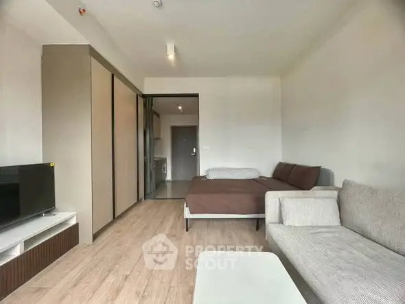 Modern studio apartment with cozy living area and bed, featuring sleek furniture and neutral tones.
