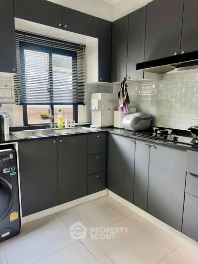 Modern kitchen with sleek black cabinets and large windows