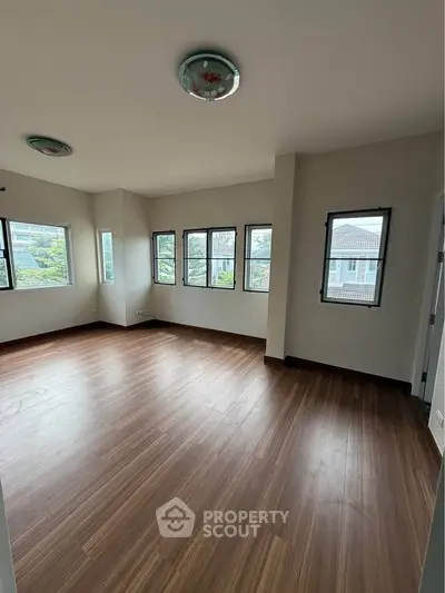 Spacious empty room with large windows and wooden flooring, perfect for customization.