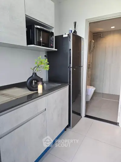 Modern kitchen with sleek cabinetry and stainless steel appliances adjacent to a stylish bathroom.