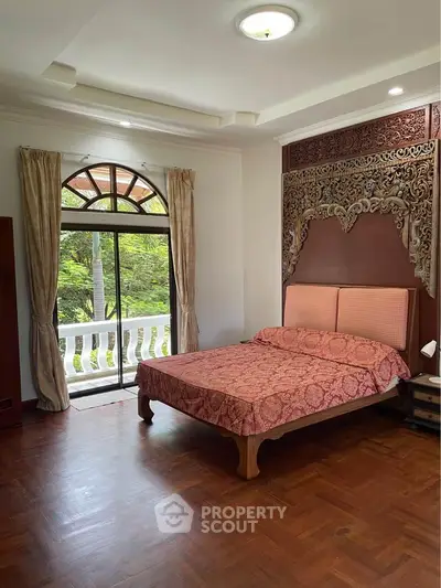 Elegant bedroom with ornate headboard and large window overlooking greenery