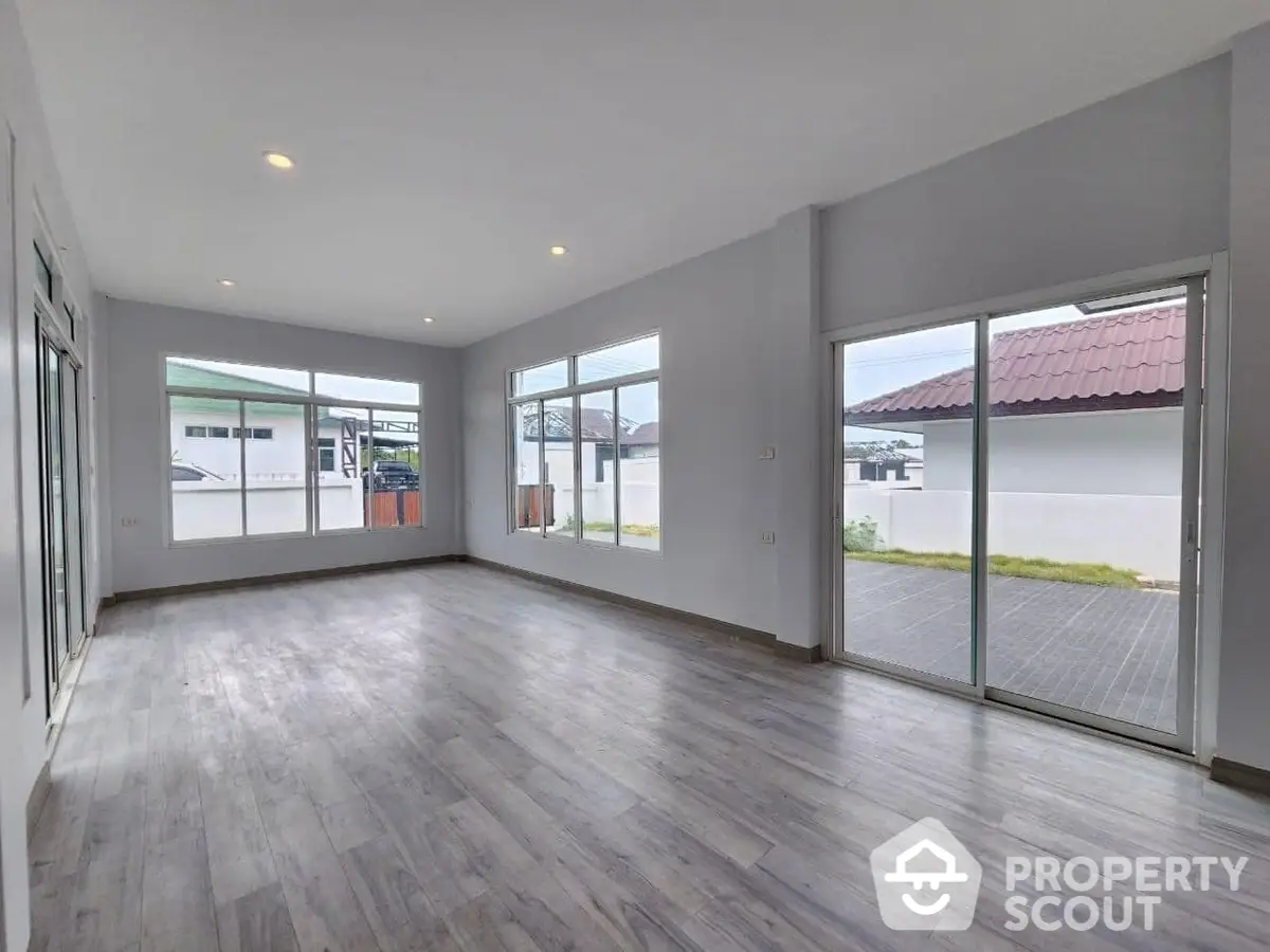 Spacious and bright living area with large windows and modern flooring, perfect for family gatherings and entertainment.