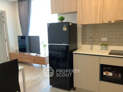 Modern kitchen with sleek black fridge and stylish cabinetry in cozy apartment