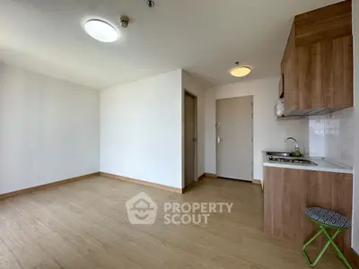 Spacious modern studio apartment with wooden flooring and compact kitchen area.