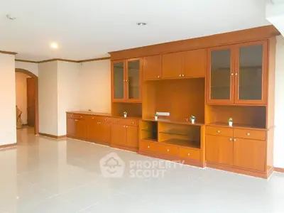Spacious living room with elegant wooden cabinetry and glossy tiled flooring