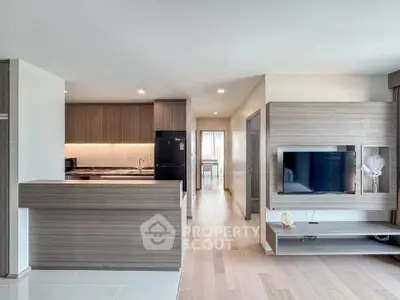 Modern open-plan kitchen and living room with sleek wooden finishes and integrated appliances.
