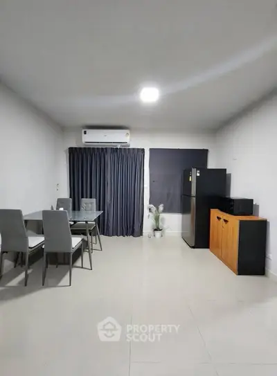 Modern dining area with sleek furniture and appliances in a minimalist apartment.